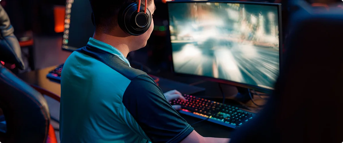 Een esports-speler met een gamingheadset op, die aan een pc speelt in een donkere gamingarena met een krachtige monitor en een RGB-toetsenbord.