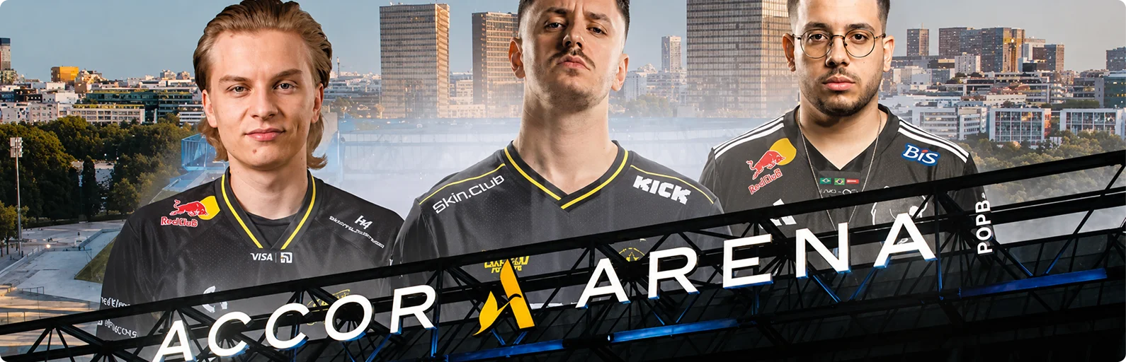 Drie professionele esports-spelers poseren voor een promotiefoto van hun team voor de achtergrond met het logo van Accor Arena.