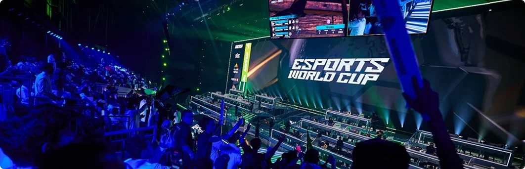 Een grote arena voor esports-toernooien, vol met toeschouwers en verlicht door blauwe podiumverlichting tijdens een live gamingwedstrijd.